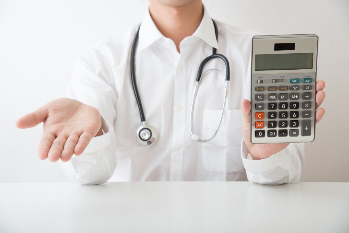 Medico che chiede il pagamento della parcella dopo aver fatto i calcoli con la calcolatrice