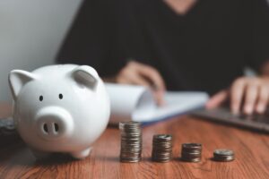 Persona che fa dei calcoli, salvadanaio e monete