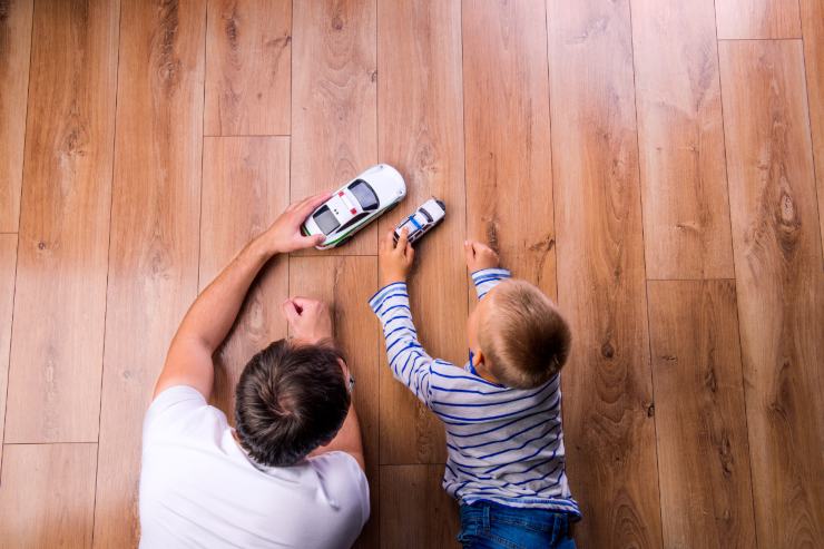 papà e figlio giocano a macchinine su pavimento